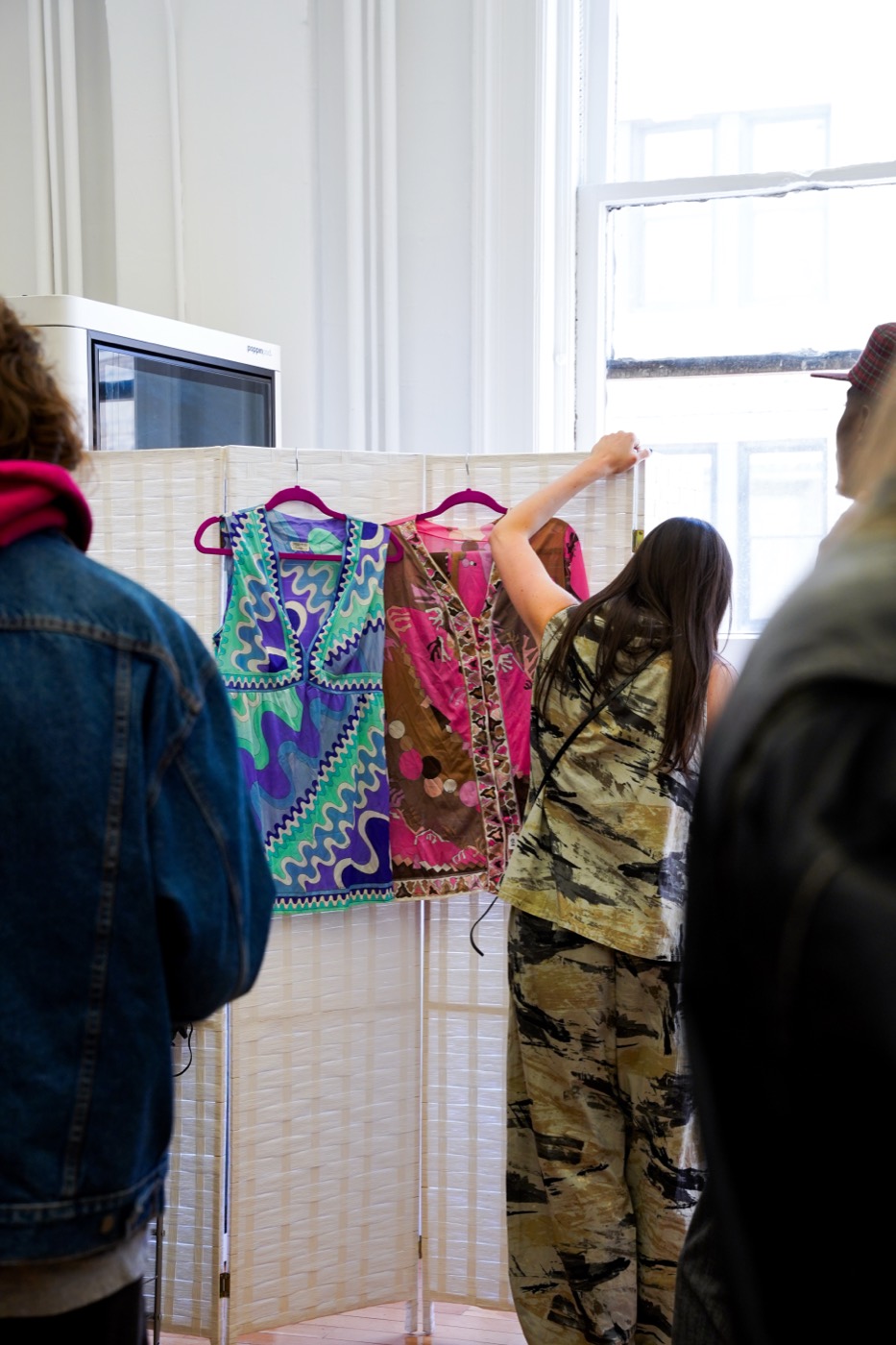 Shoppers browsing a rack of printed vintage dresses